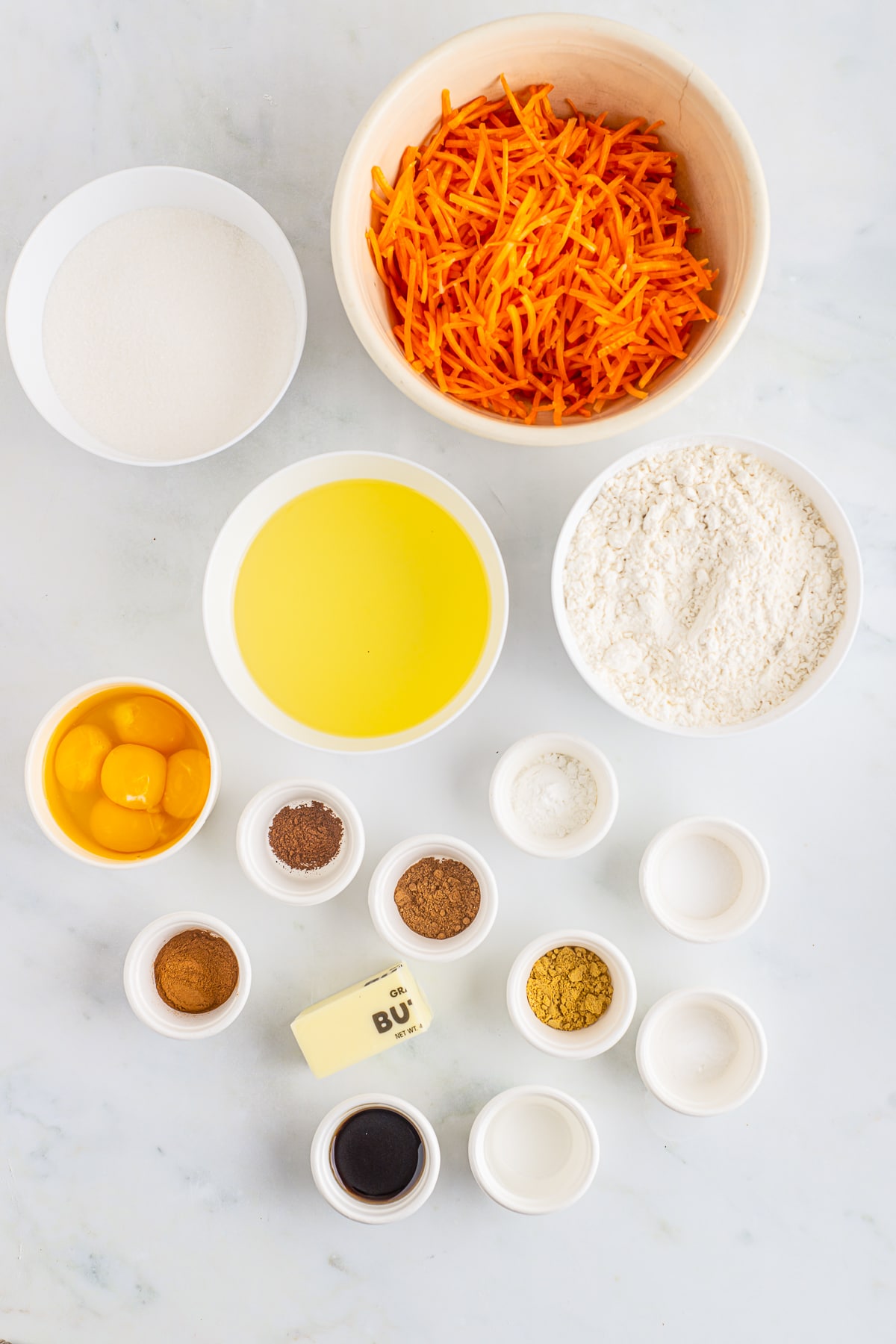Overhead image of ingredients needed to make carrot bundt cake on a white table top