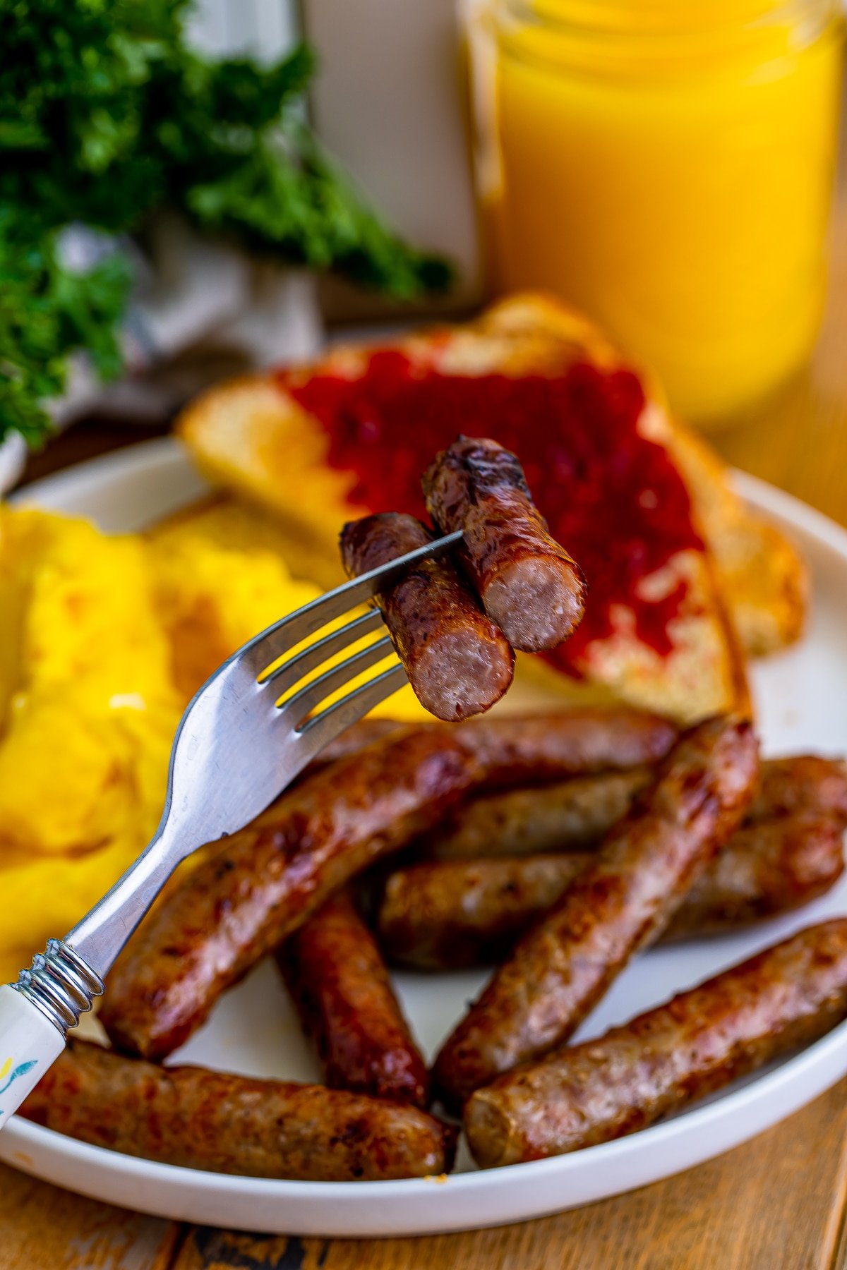 A silver fork holding up an air fryer breakfast sausage in air