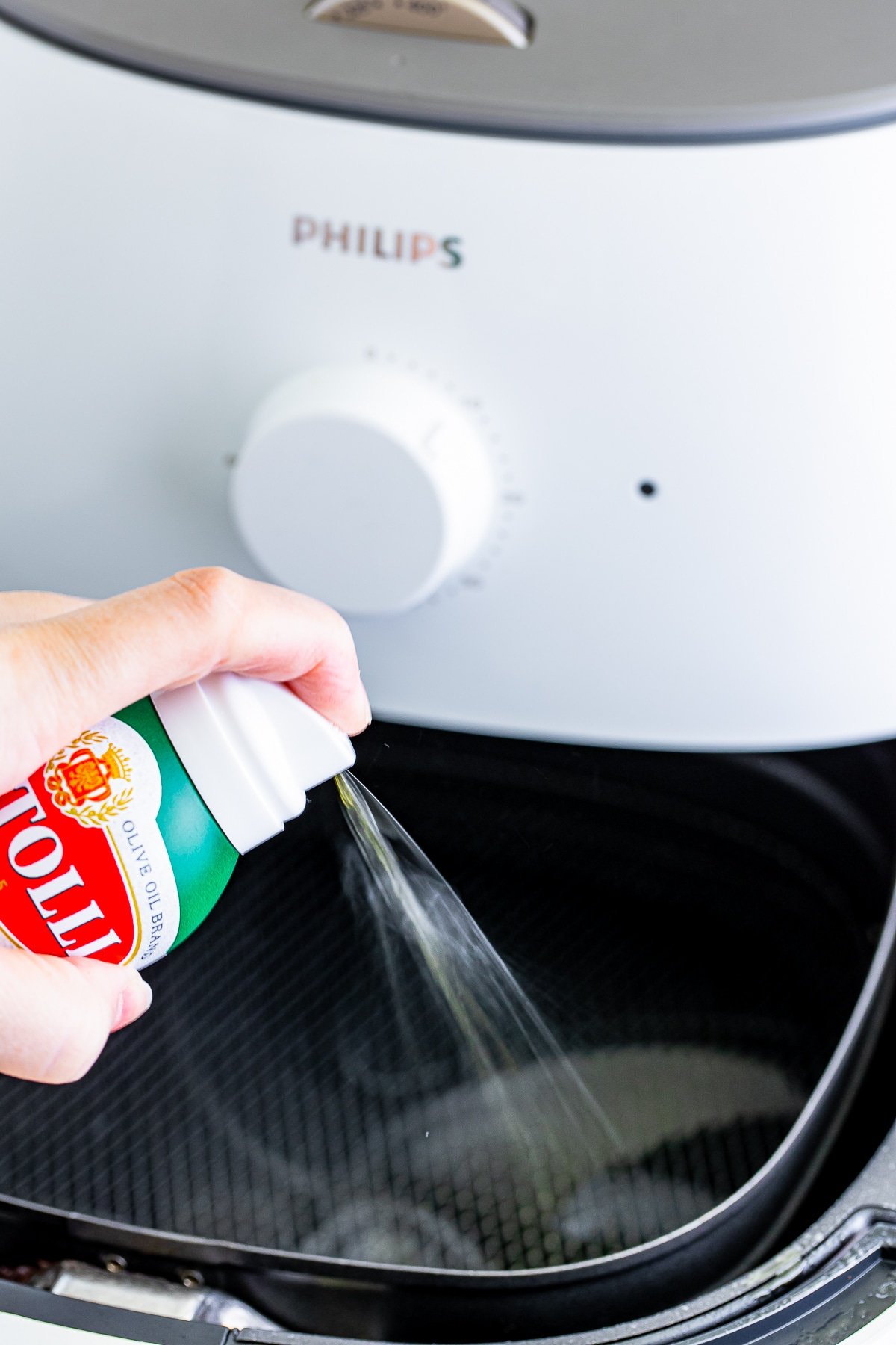 Image showing olive oil spray being sprayed into a white air fryer