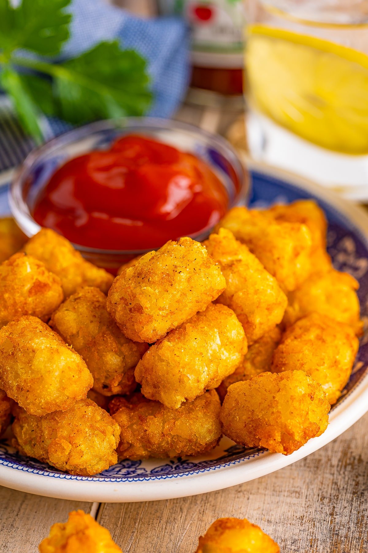 The best crispy air fryer tater tots on a blue plate on a wooden table top served with ketchup