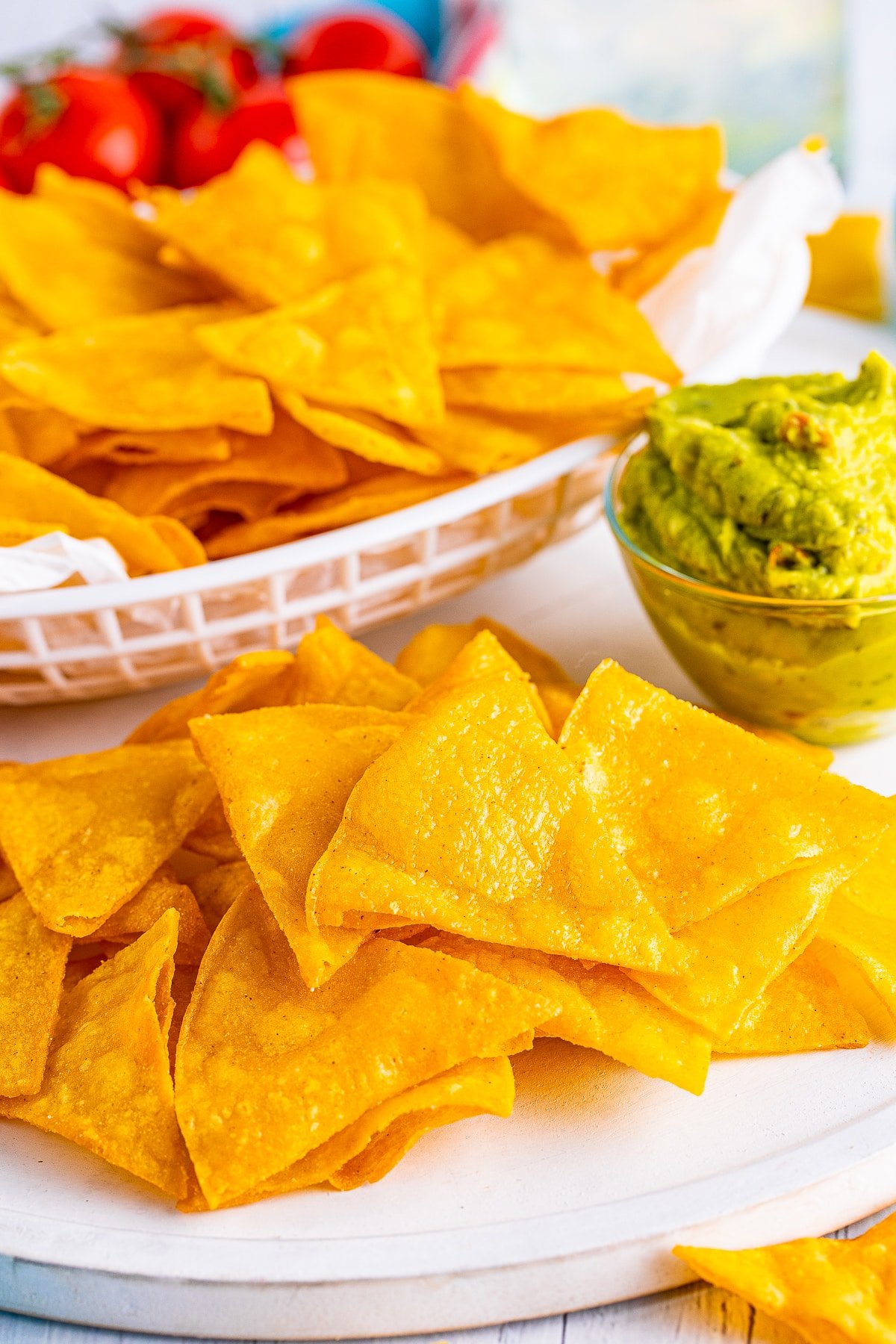 Upclose image of homemade fried tortilla chips on a white serving platter with guacamole