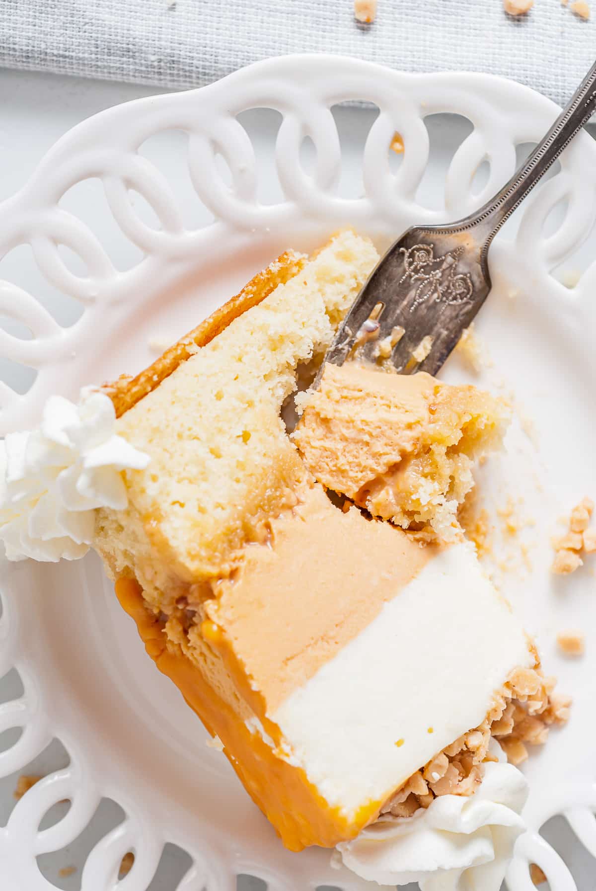 A silver fork taking out a bite of white chocolate mousse cake on a white plate