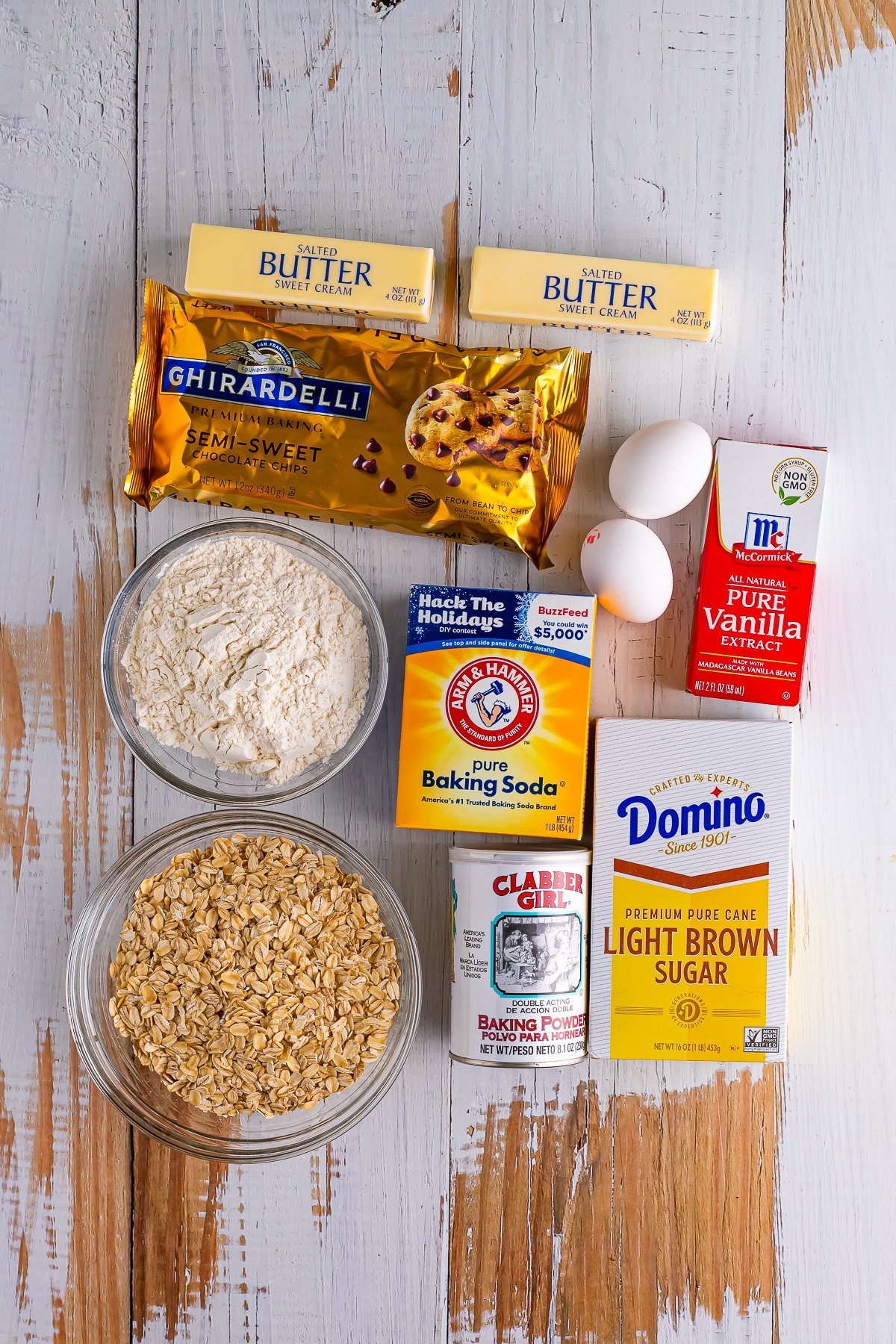 Overhead image showing the ingredients needed to make oatmeal chocolate chip cookie bars on a distressed white wood table top