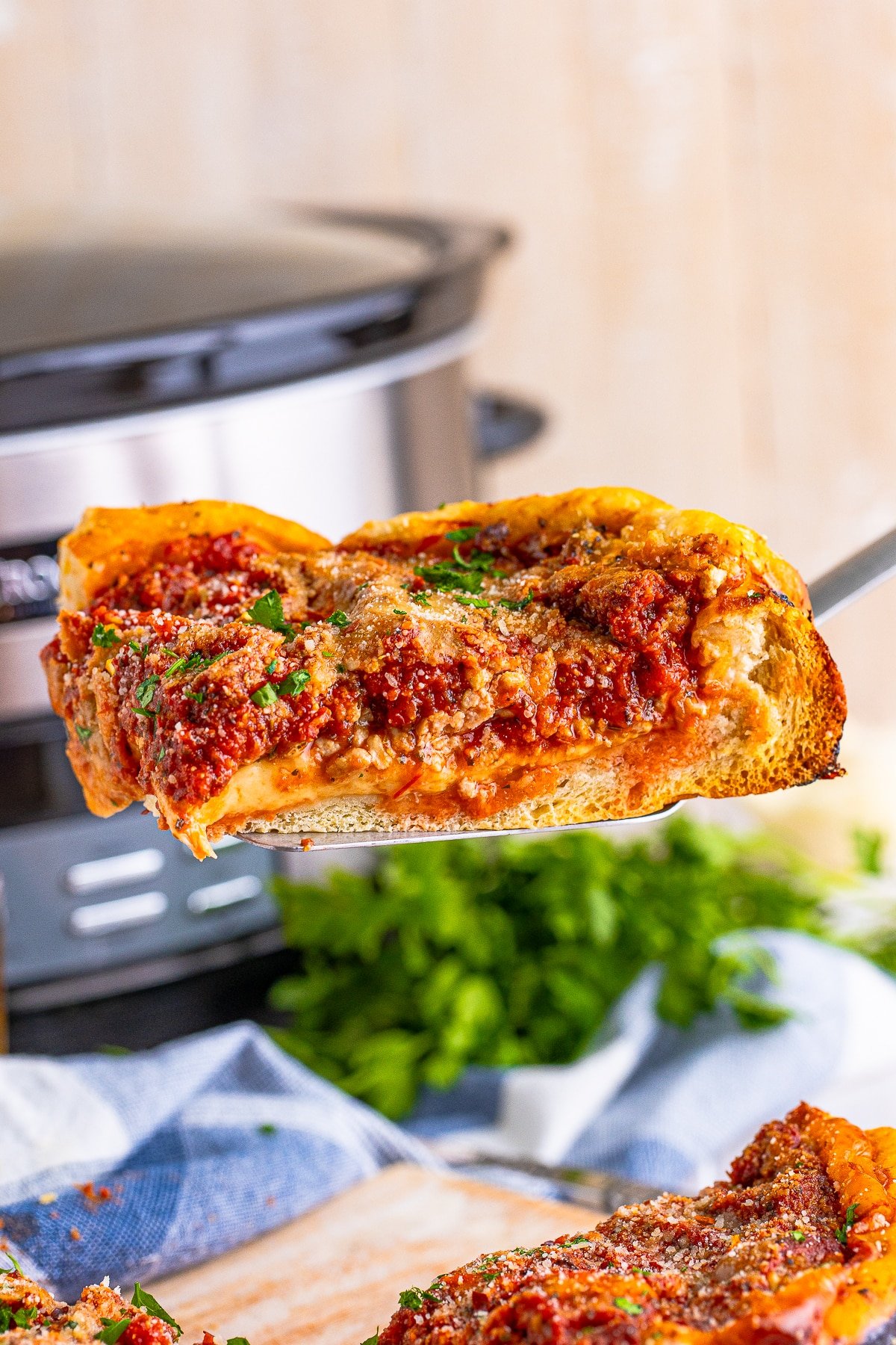 A slice of slow cooker deep-dish pizza in air on a spatula