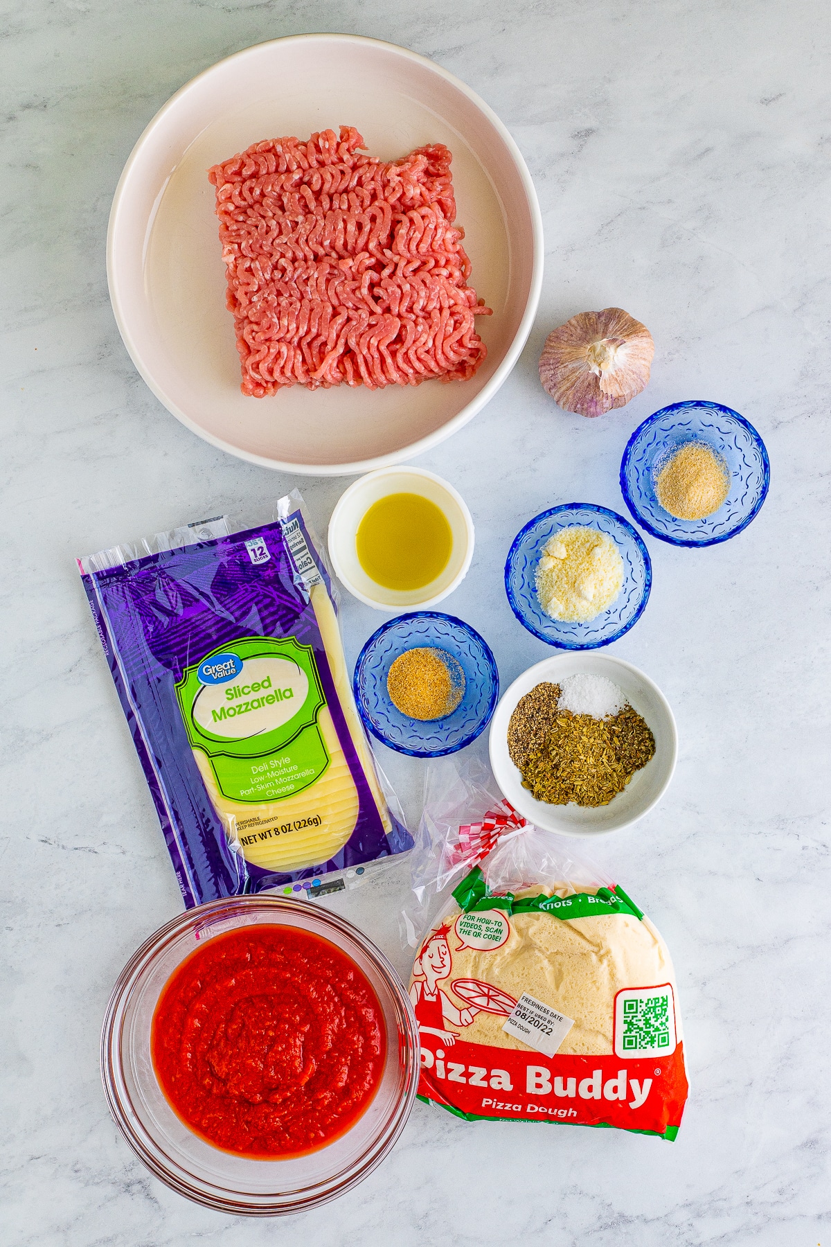 Overhead image of ingredients needed to make slow cooker deep-dish pizza on a grey marble table top