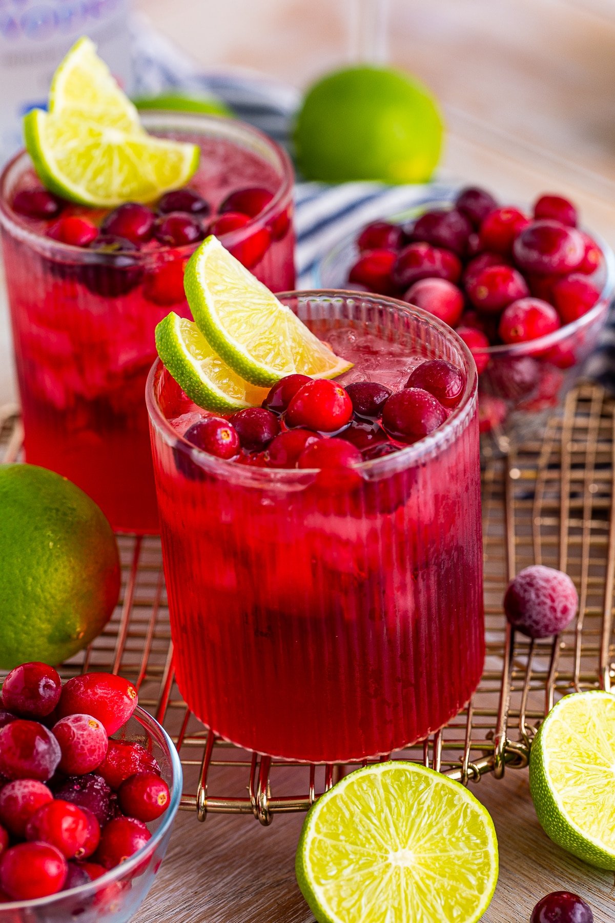 Vodka cranberry cocktails on a wire serving platter with cranberries and lime garnish