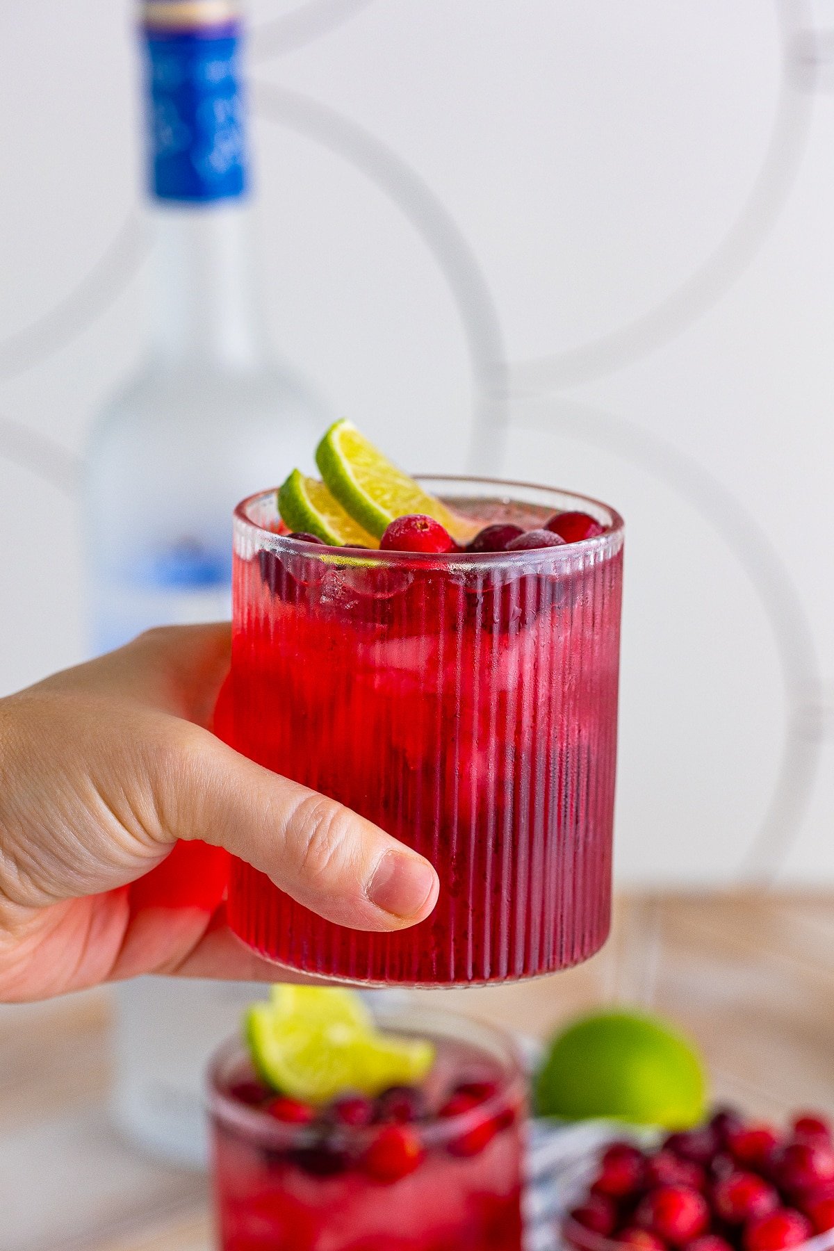 A hand holding a vodka cranberry cocktail in air