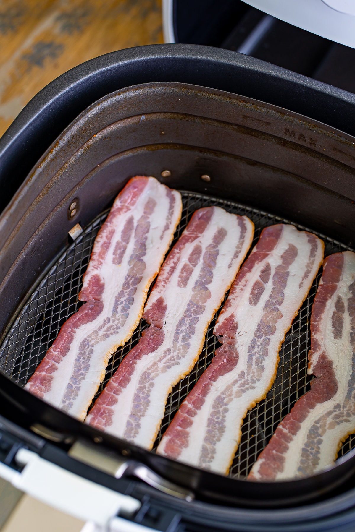 raw bacon in an air fryer basket