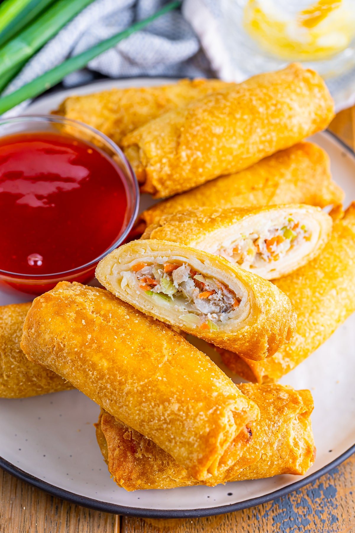 air fryer frozen egg rolls on a plate, one has been cut open to see the filling