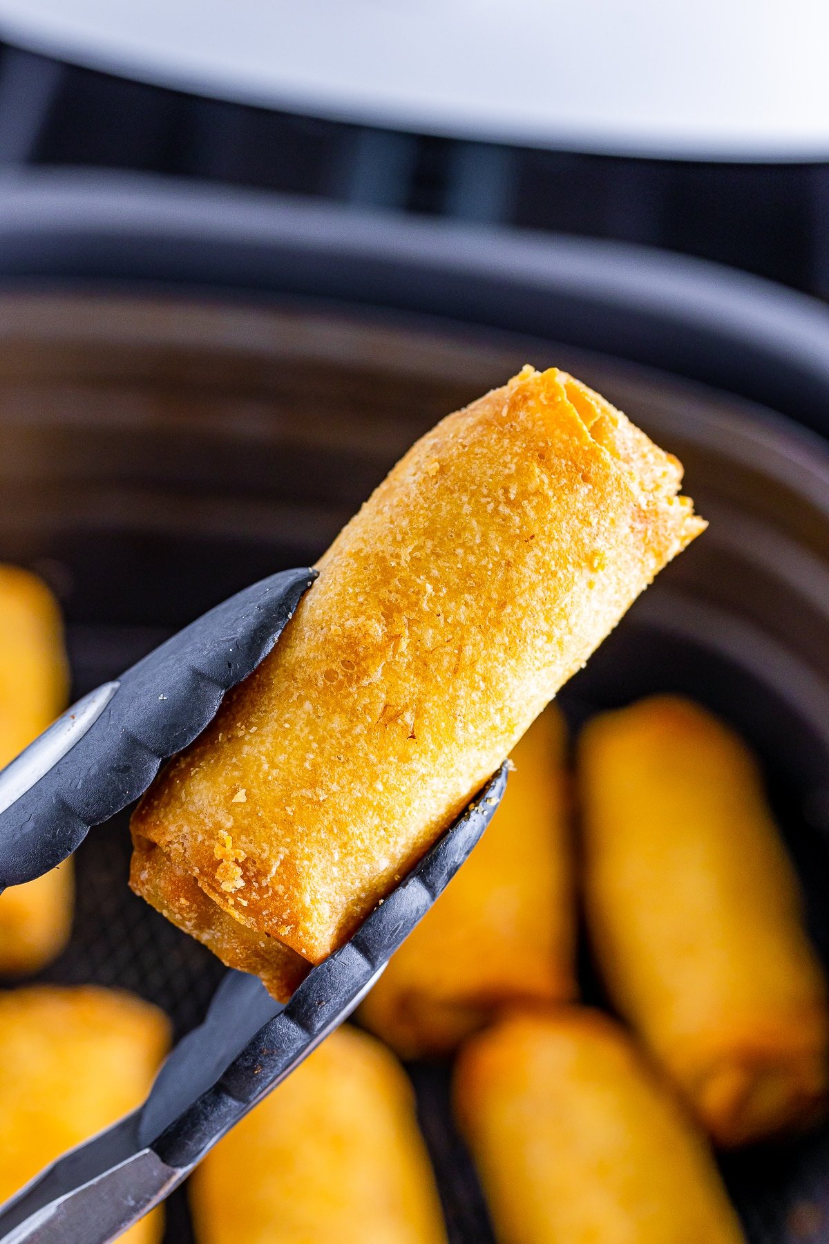 air fryer egg roll in air with tongs
