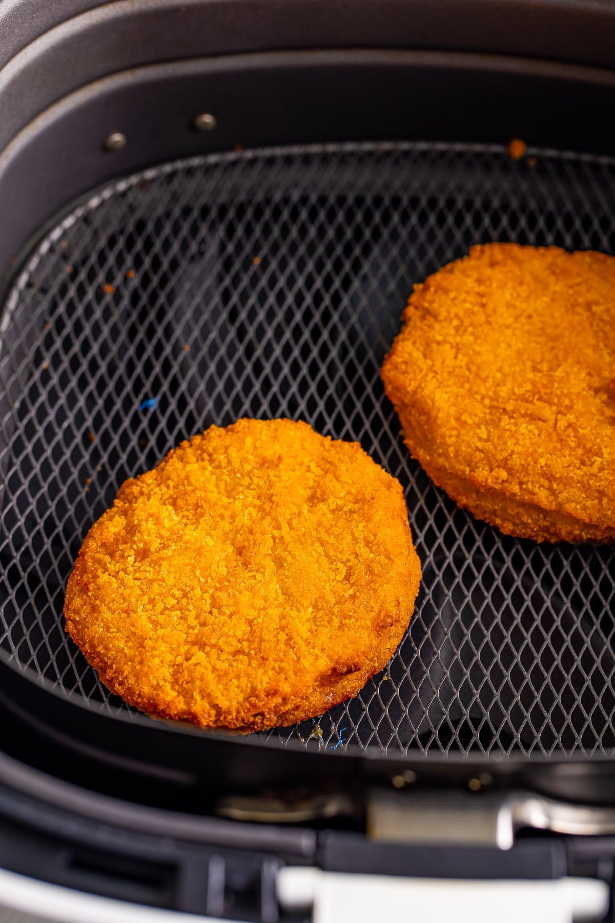 cooked air fryer frozen chicken patties in the basket of a white air fryer