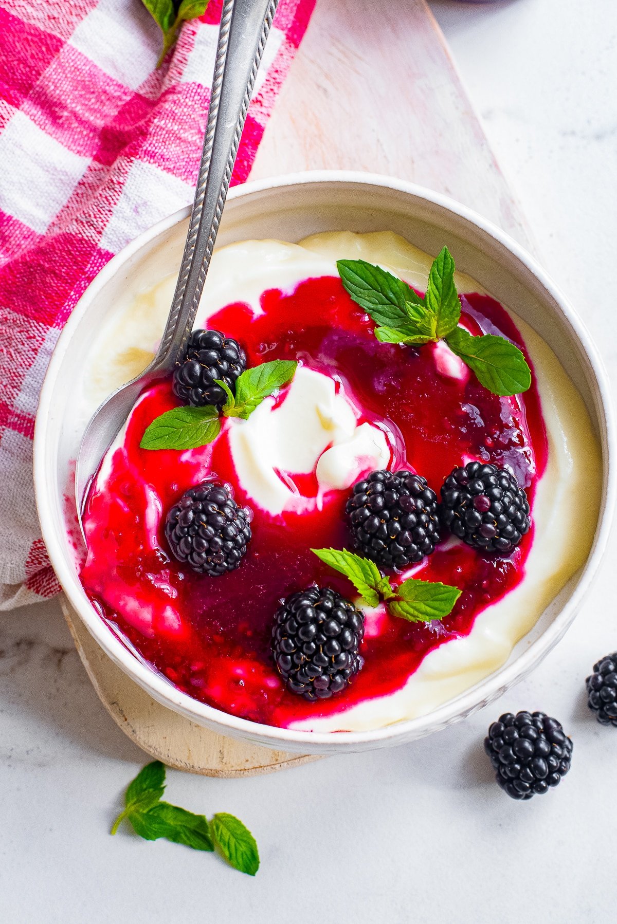 Overhead image of blackberry sauce on top of yogurt in a bowl