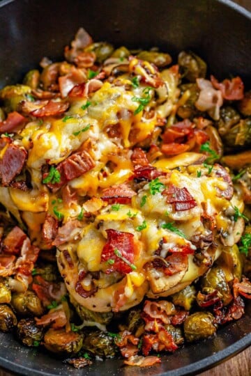 Alice Springs chicken topped with honey mustard, bacon, mushrooms, and melted colby jack cheese in a skillet.