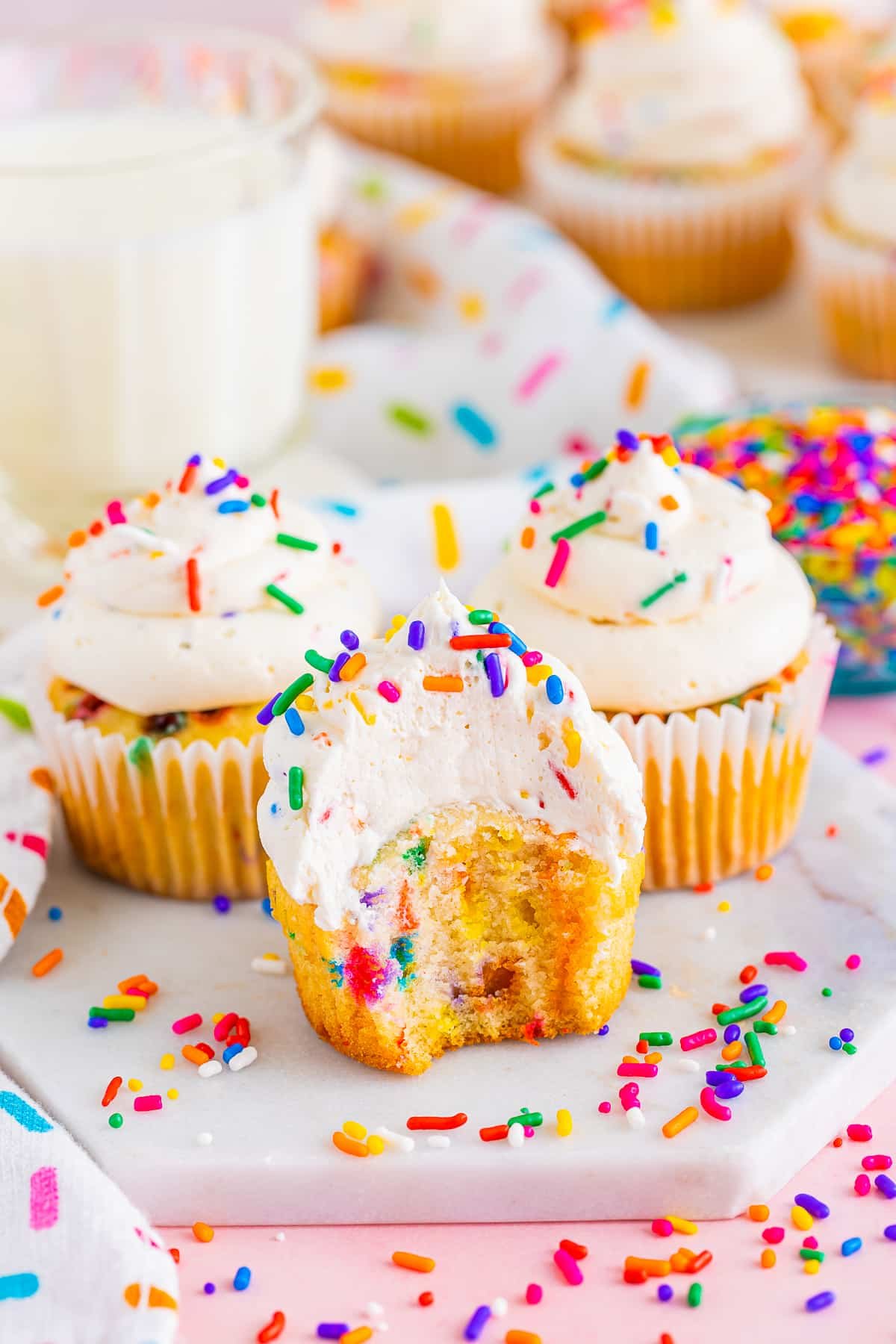 Funfetti cupcake with a bite taken out on a white marble serving platter