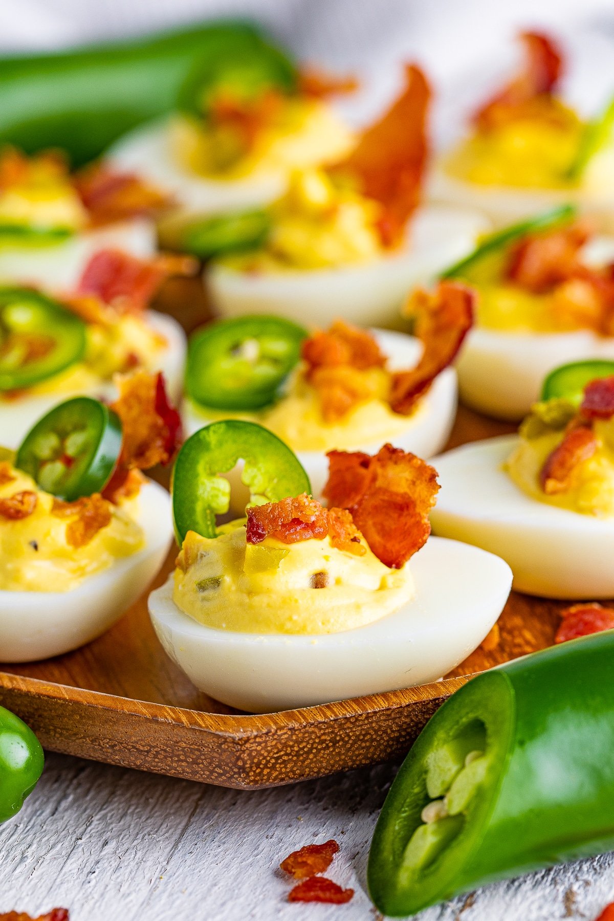 Jalapeno deviled eggs on a wooden serving plate