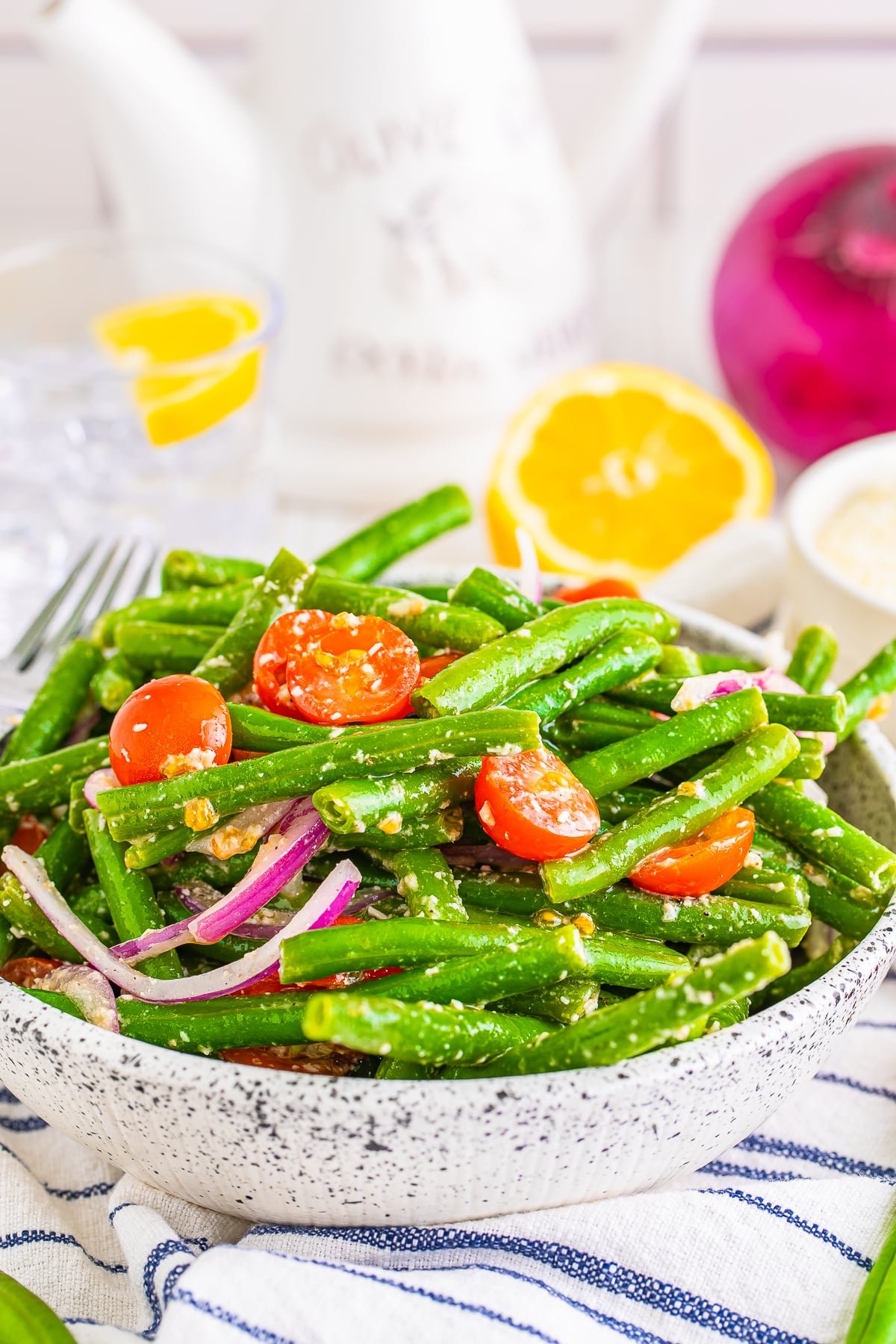 45 degree angle shot showing cold green bean salad in a speckled bowl