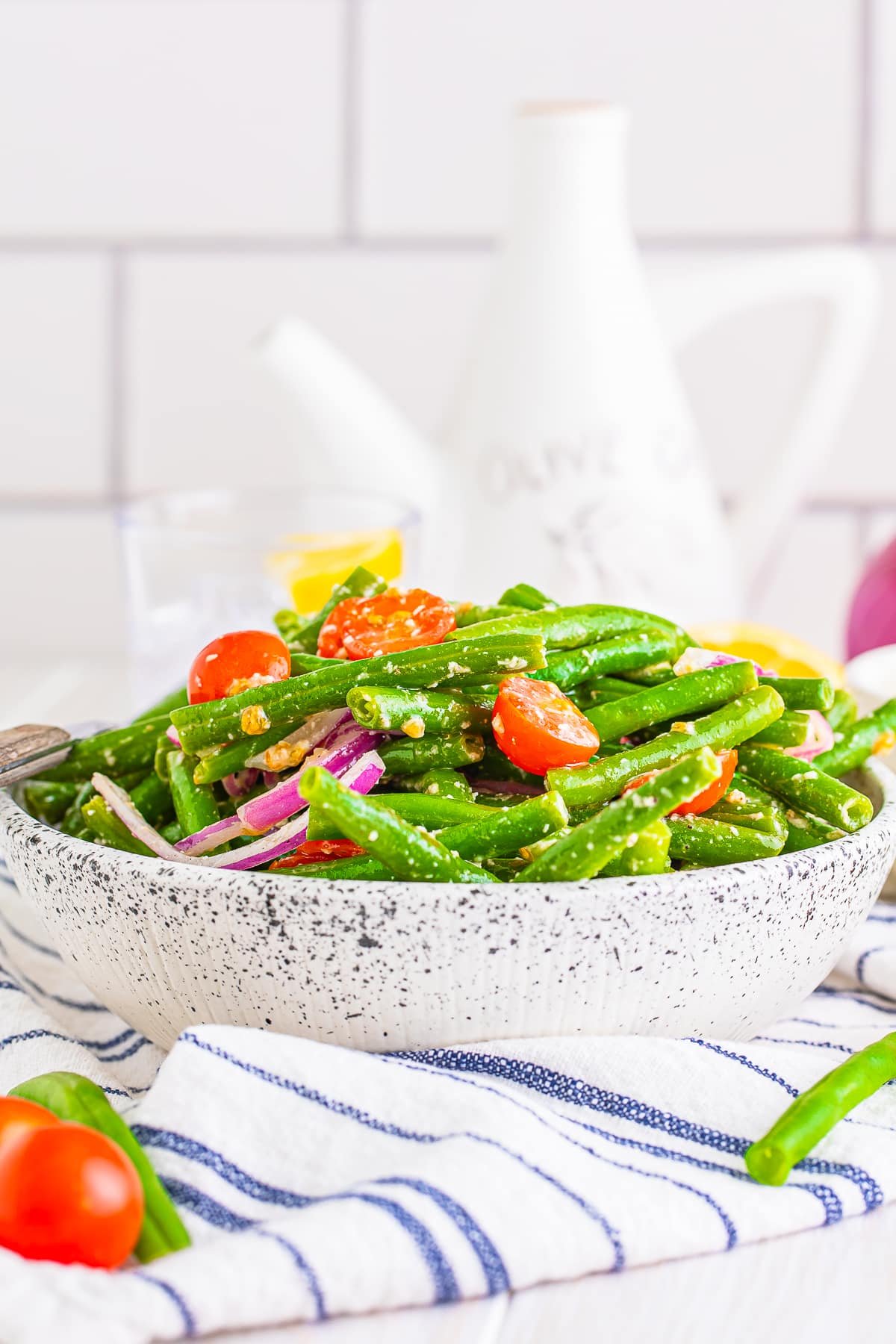 Far away image of cold green bean salad in a speckled bowl