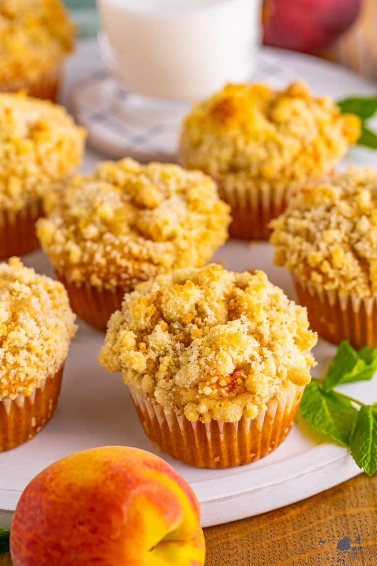 A platter of peach muffins topped with golden streusel crumble.