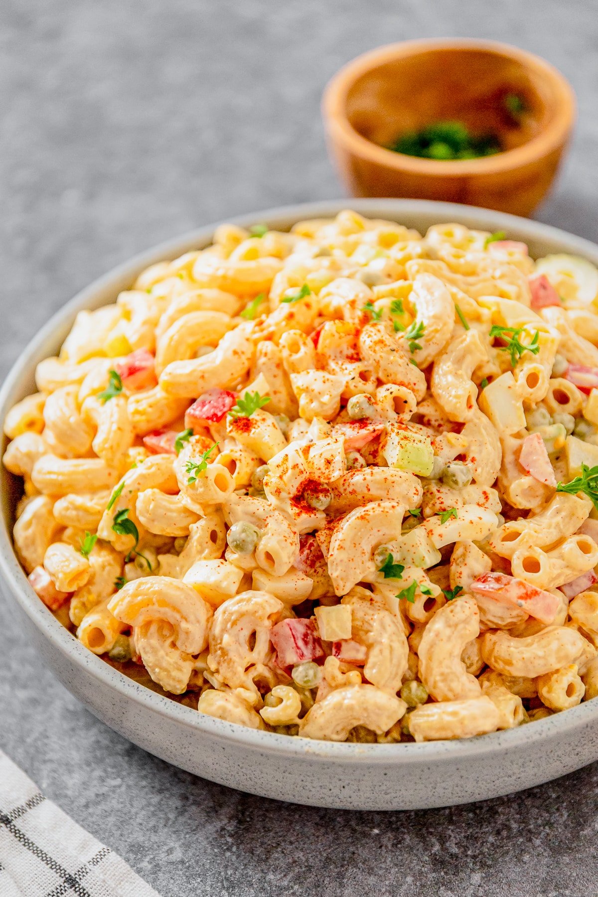 45 degree angle image of macaroni salad with peas in a grey bowl