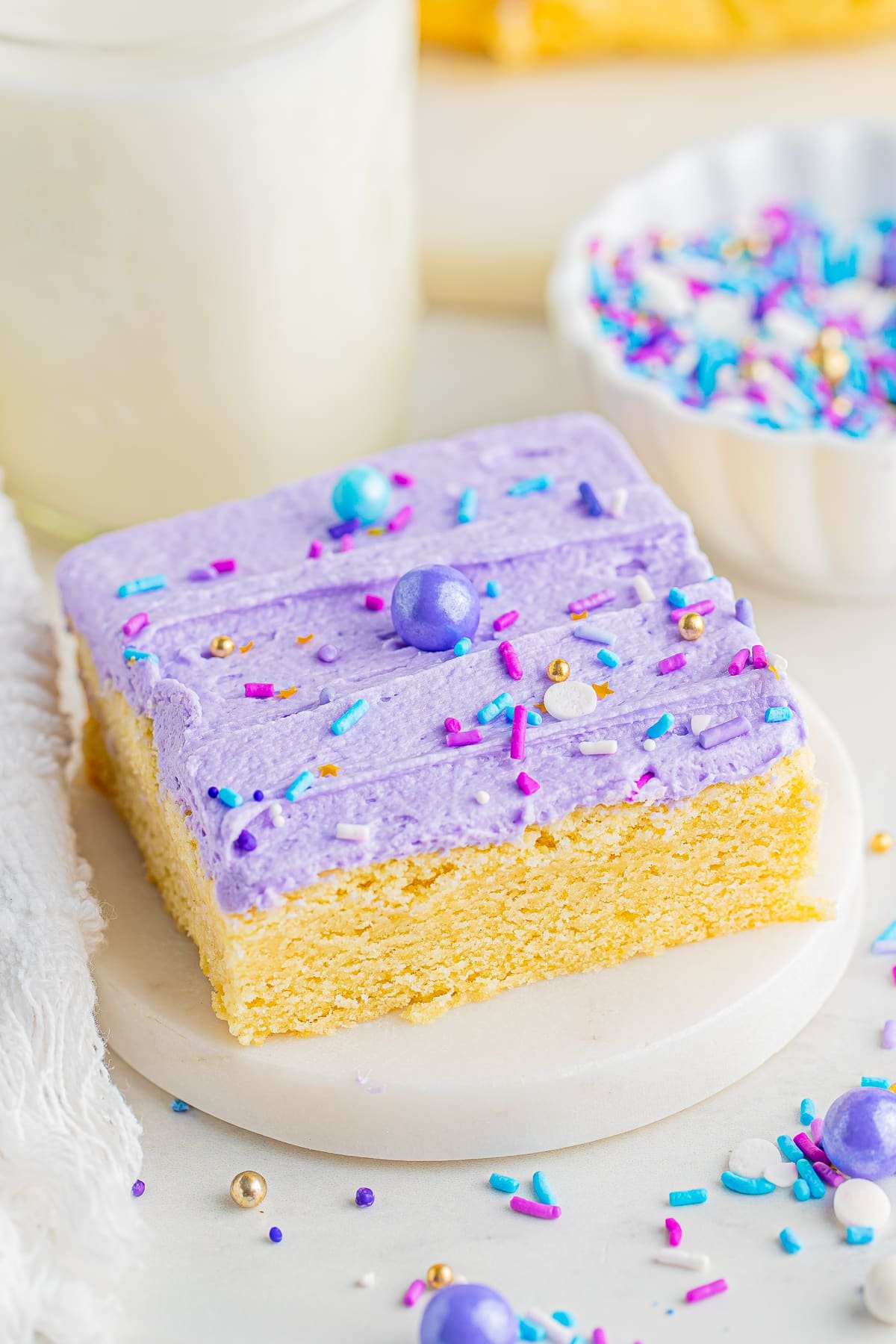 A frosted sugar cookie bar on a small white marble plate