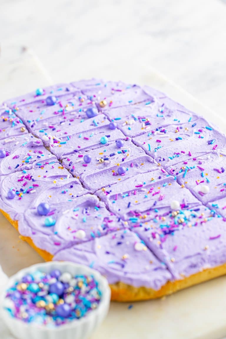 Frosted sugar cookie bars with purple buttercream and sprinkles cut into squares.