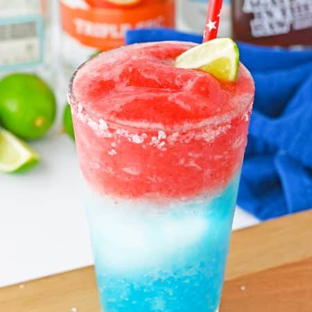 A layered red white and blue 4th of July margarita cocktail garnished with lime.