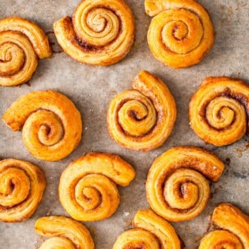 Mini Cinnamon Rolls on parchment paper dusted with powdered sugar.