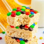 Stacked M&M rice krispie treats with peanut butter frosting and colorful candy.