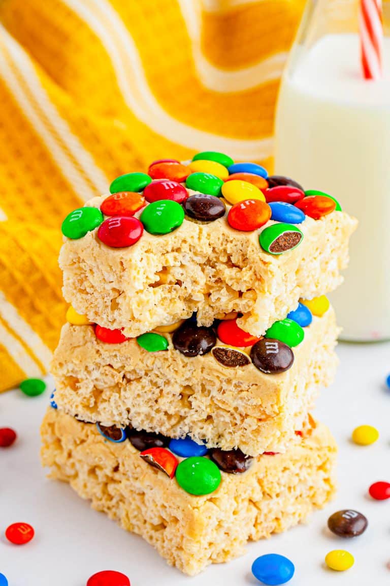 Stacked M&M rice krispie treats with peanut butter frosting and colorful candy.