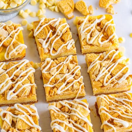 Golden Oreo cheesecake bars cut into squares with a white chocolate drizzle and crushed cookie topping.