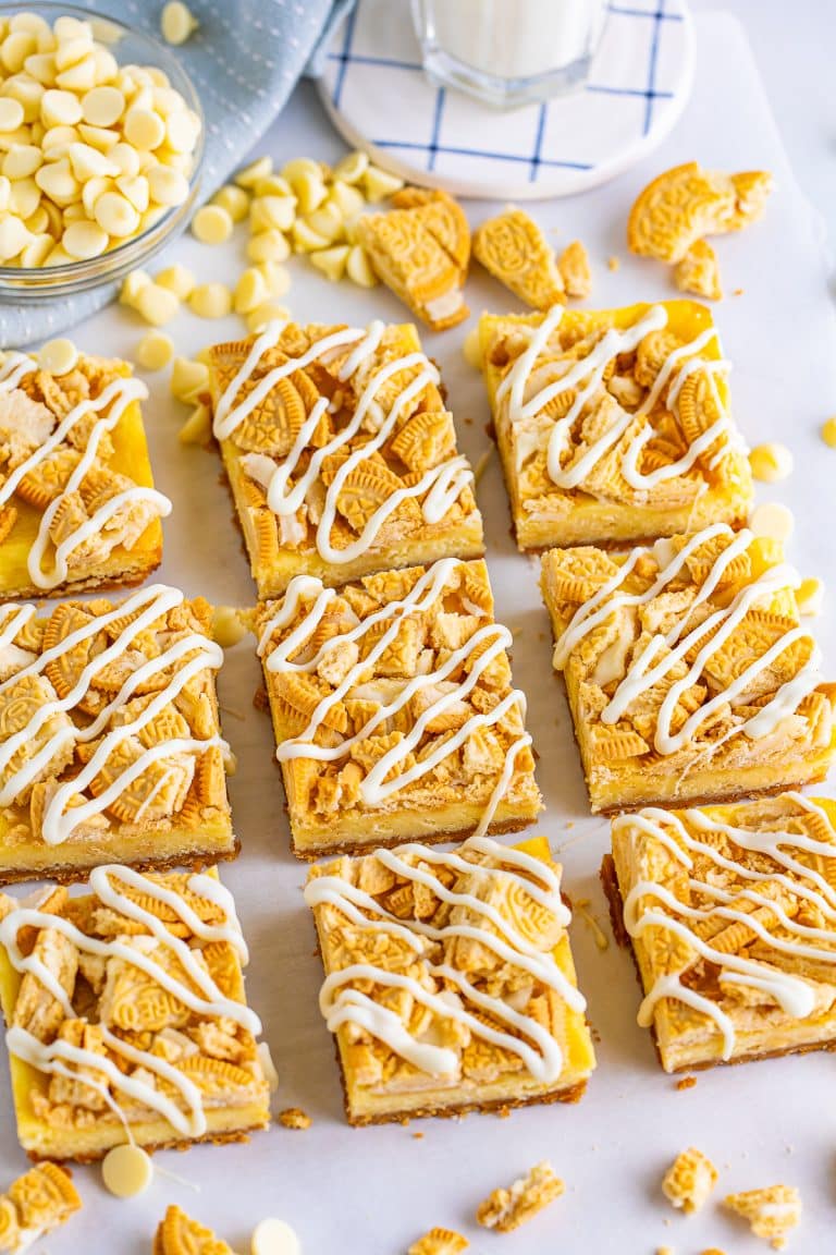 Golden Oreo cheesecake bars cut into squares with a white chocolate drizzle and crushed cookie topping.