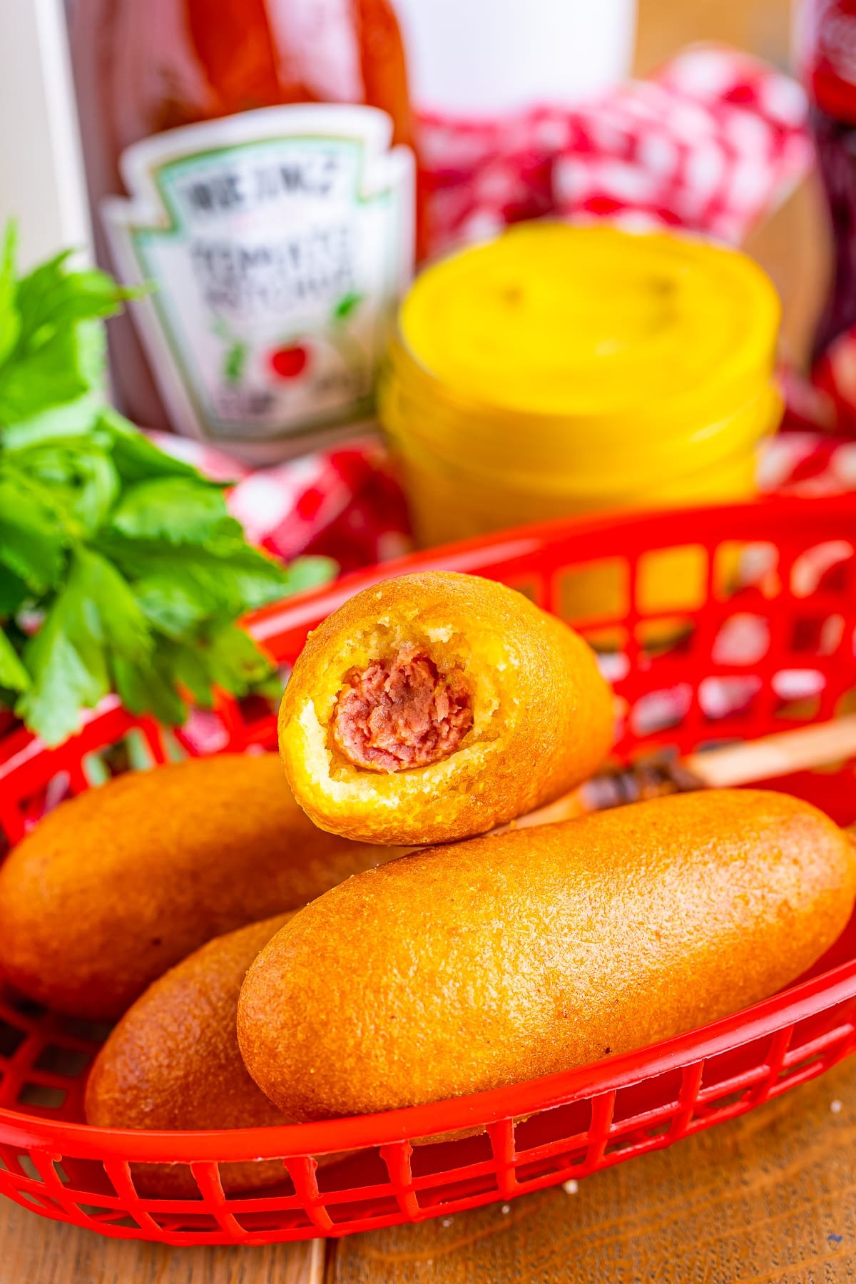 air fryer frozen corn dogs with a bite taken out in a red basket