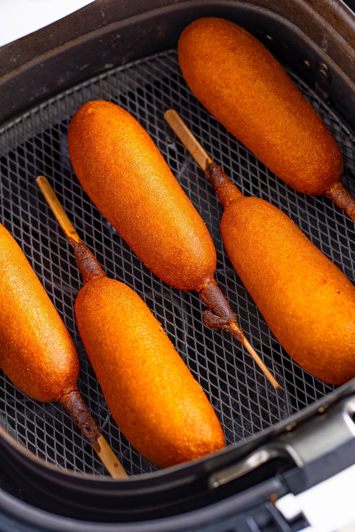 cooked corn dogs in an air fryer basket for air fryer frozen corn dogs