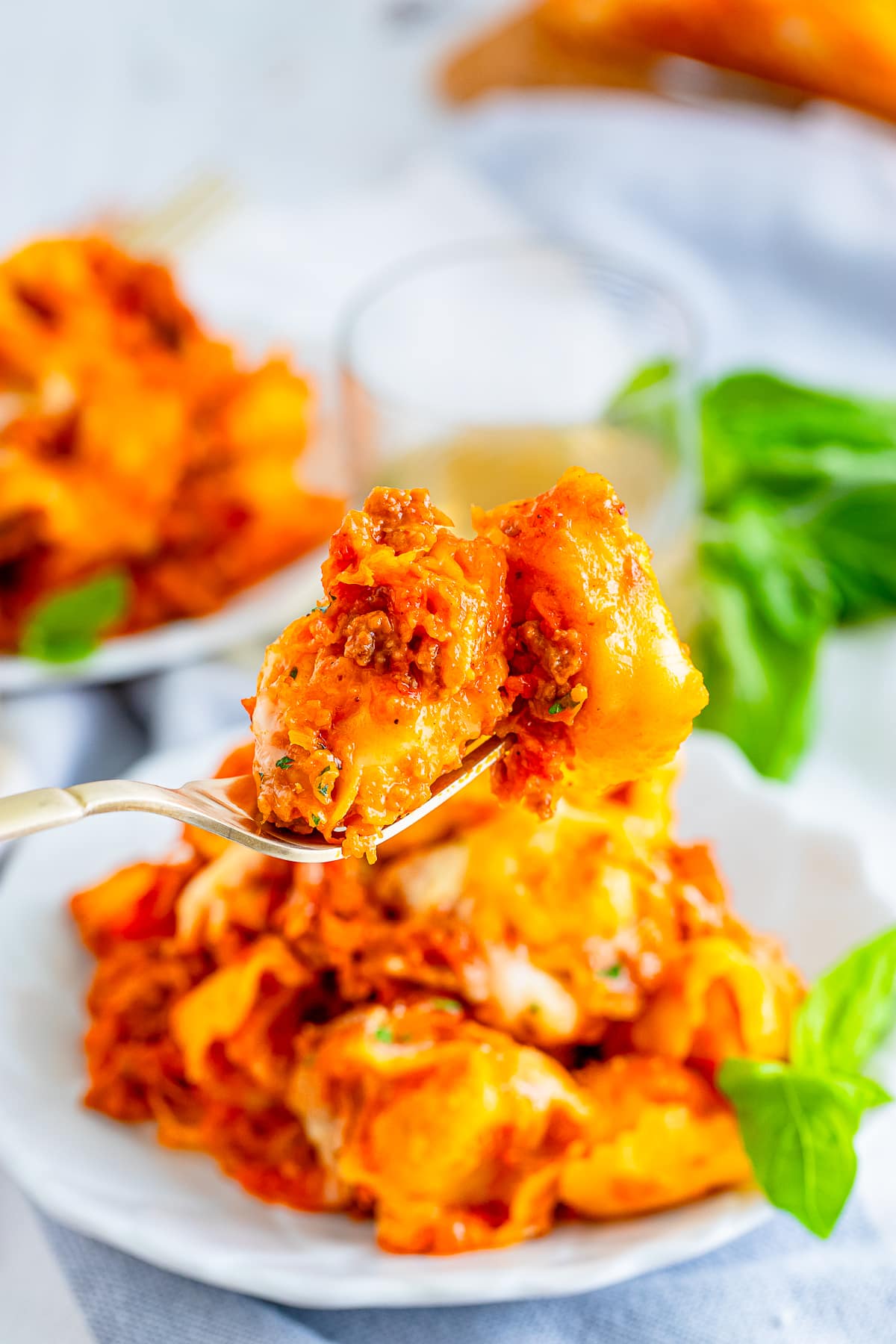 a fork holding up a bite of baked tortellini recipe in air