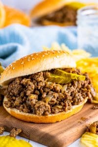 Maid Rite Recipe loose meat piled onto a sesame seed burger bun and topped with dill pickle chips, ready to serve.
