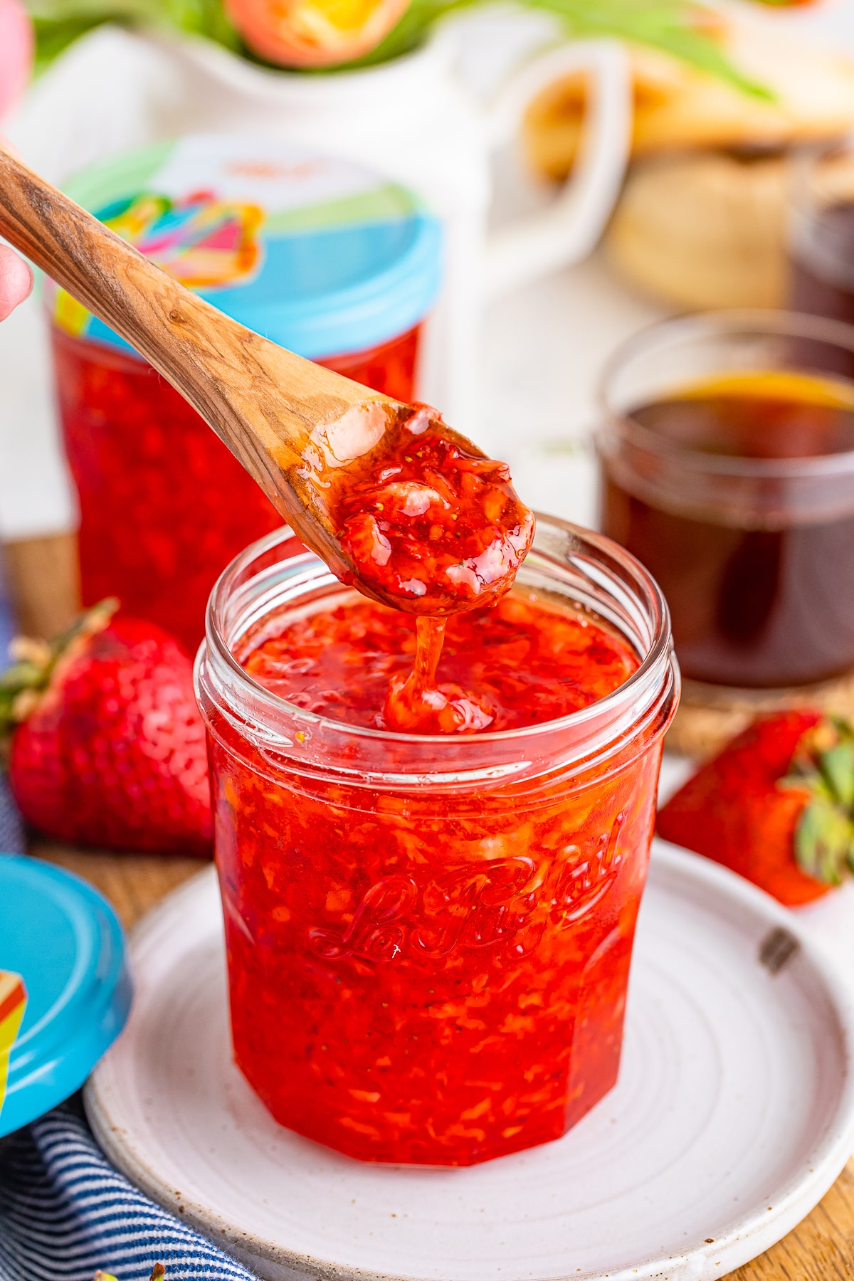 a spoon drizzling strawberry freezer jam into a glass jar