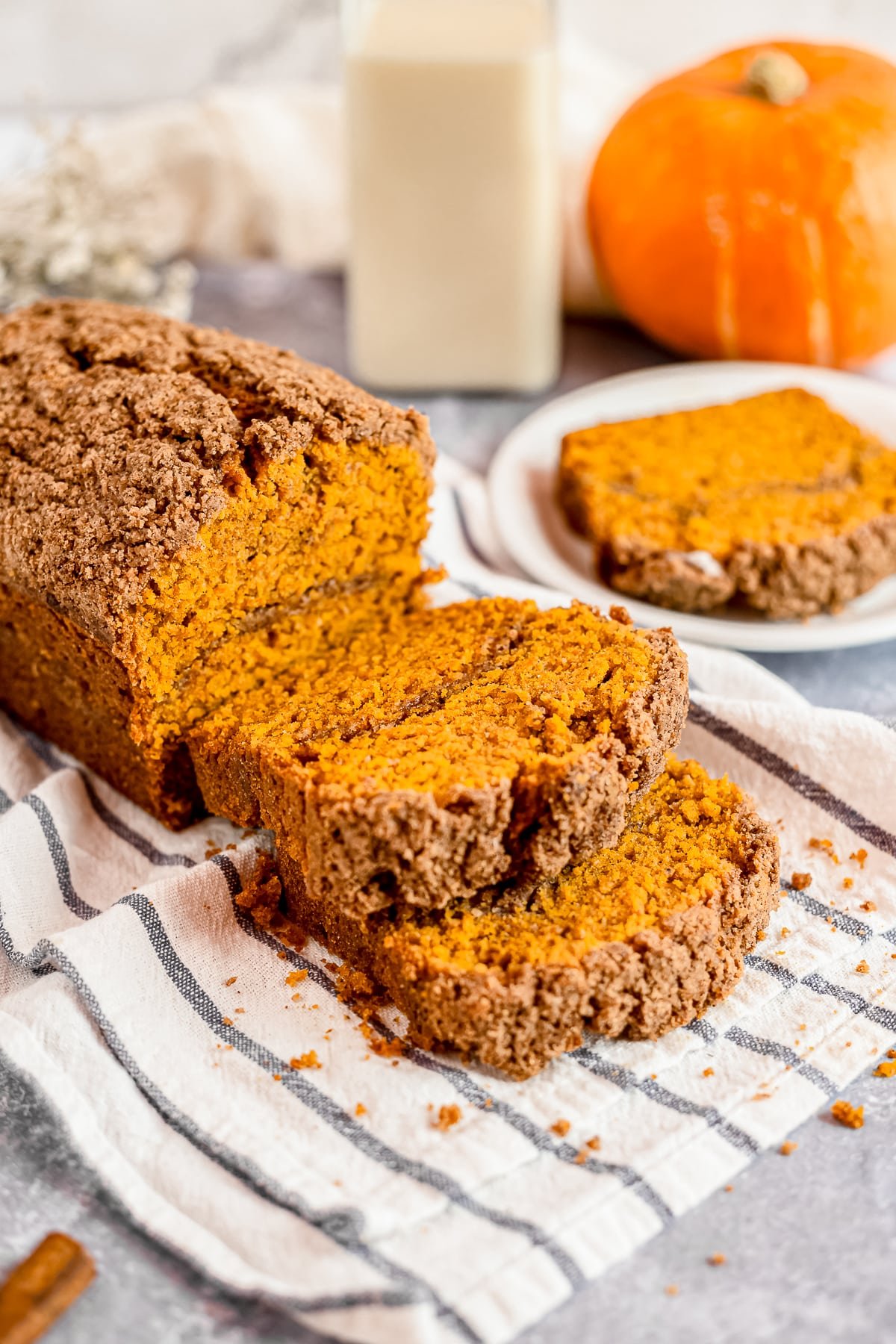 pumpkin bread with streusel topping sliced on a kitchen towel