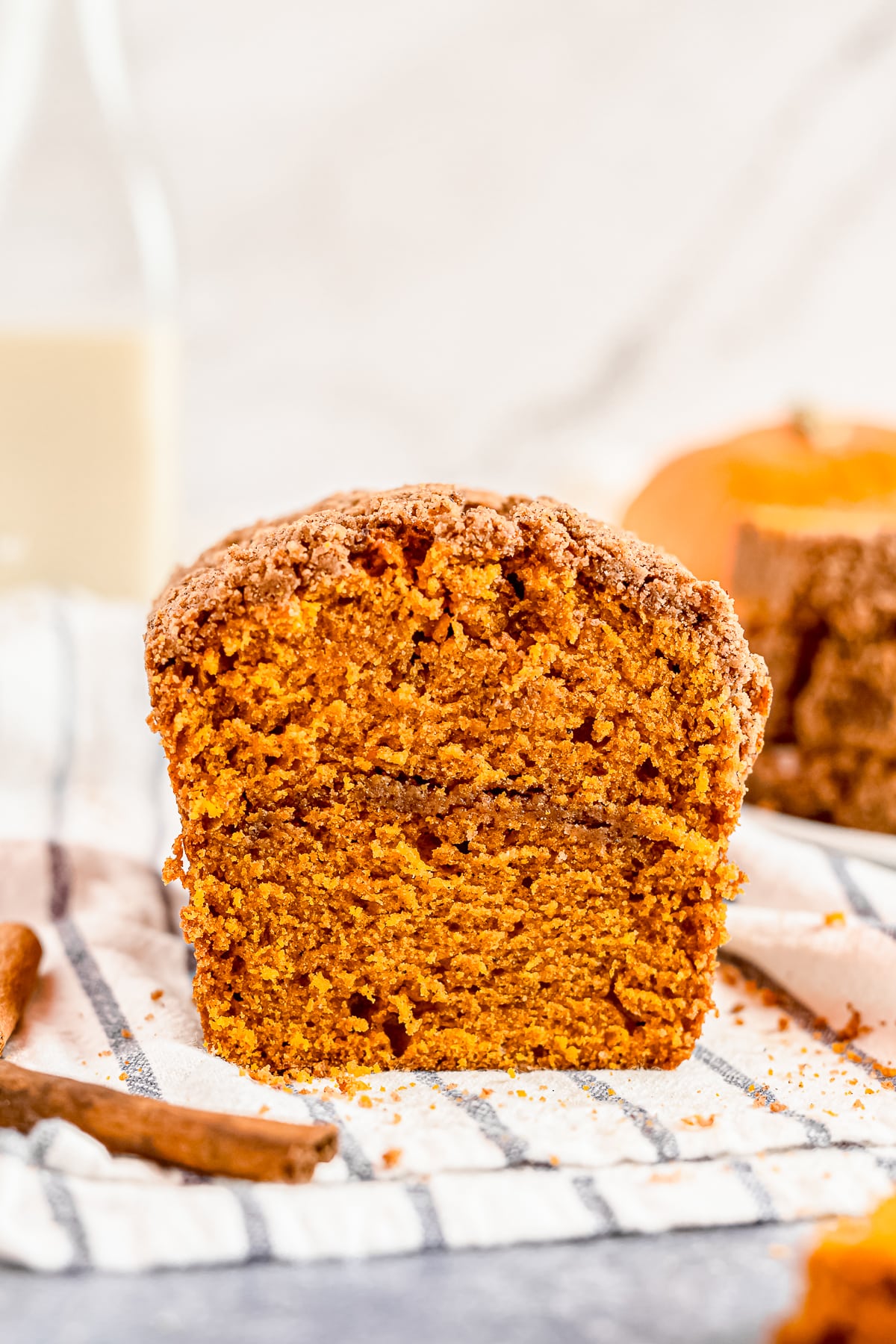 pumpkin bread with streusel topping cut in half on a kitchen towel