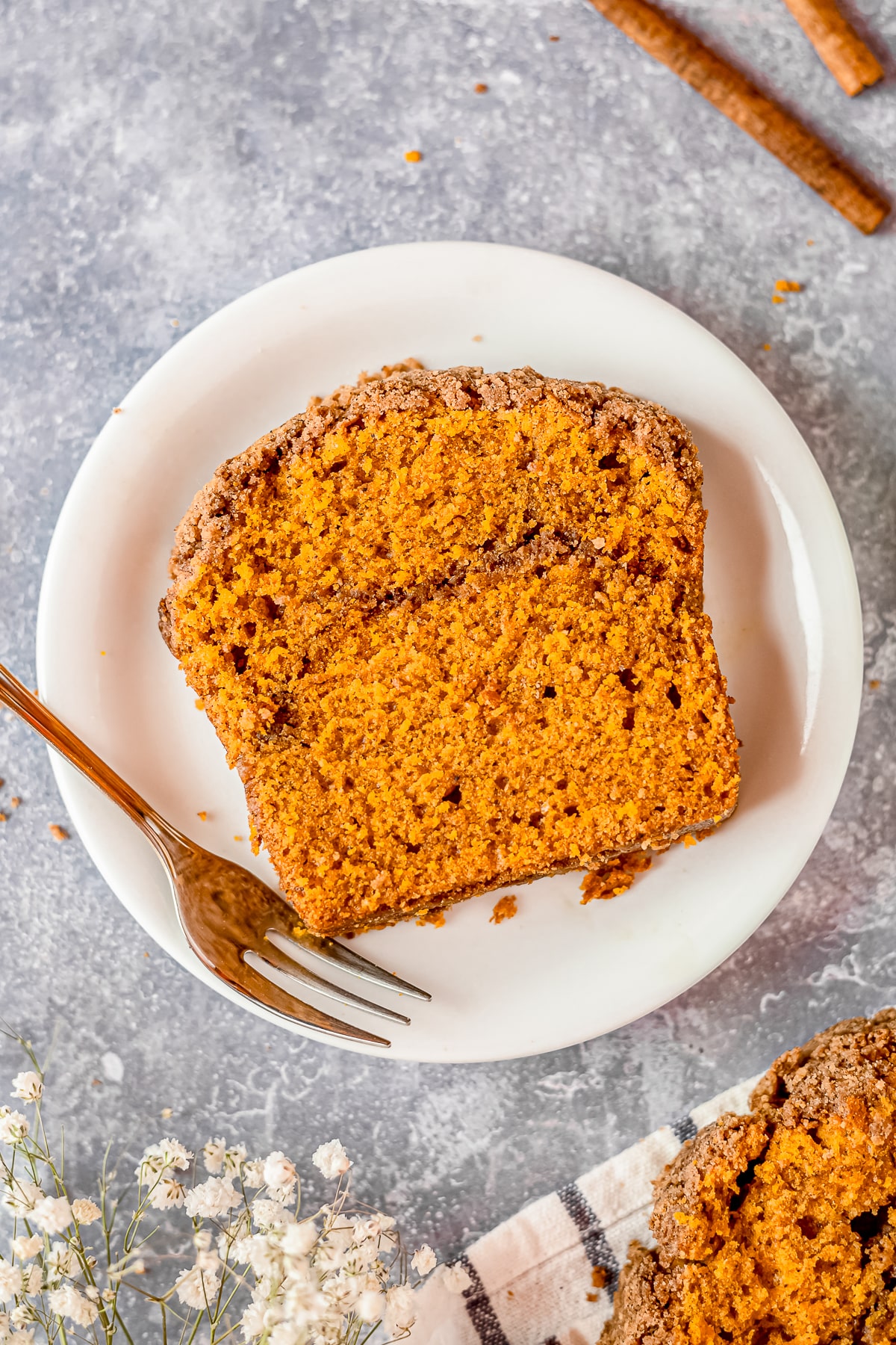 a slice of pumpkin bread with streusel topping on a white plate