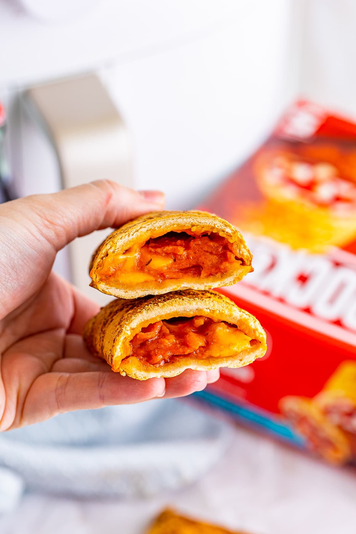 a hand holding up hot pockets in air fryer to show filling
