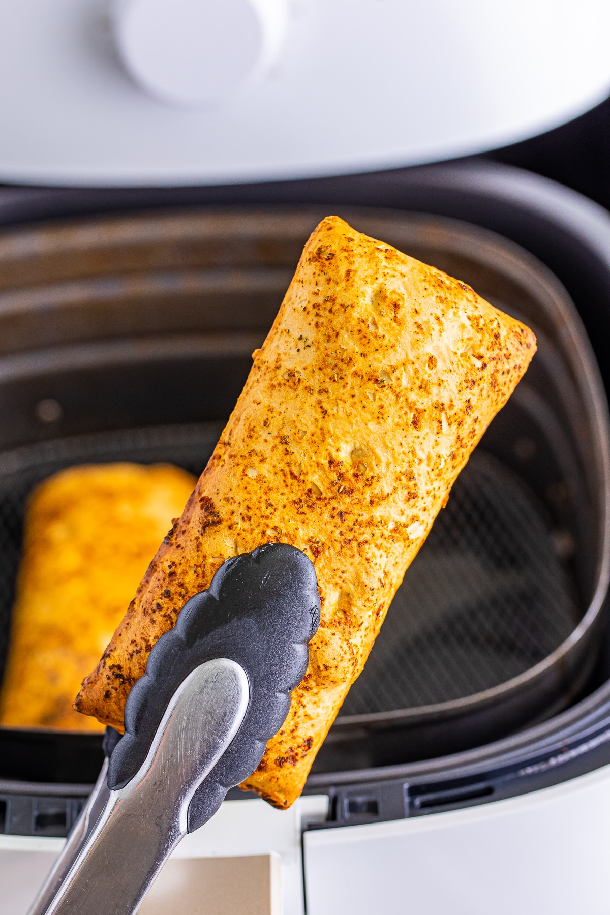 tongs holding hot pockets in air fryer in air