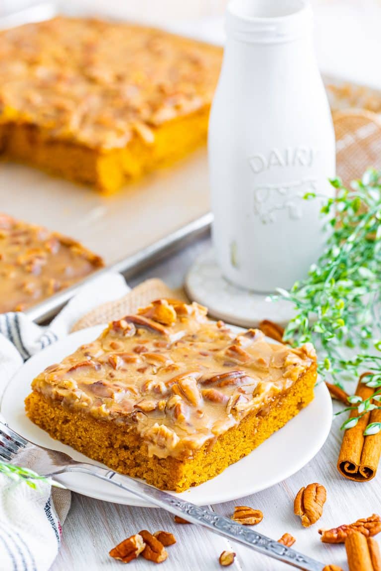 A square slice of Pumpkin Cake with bourbon praline frosting on a white plate.