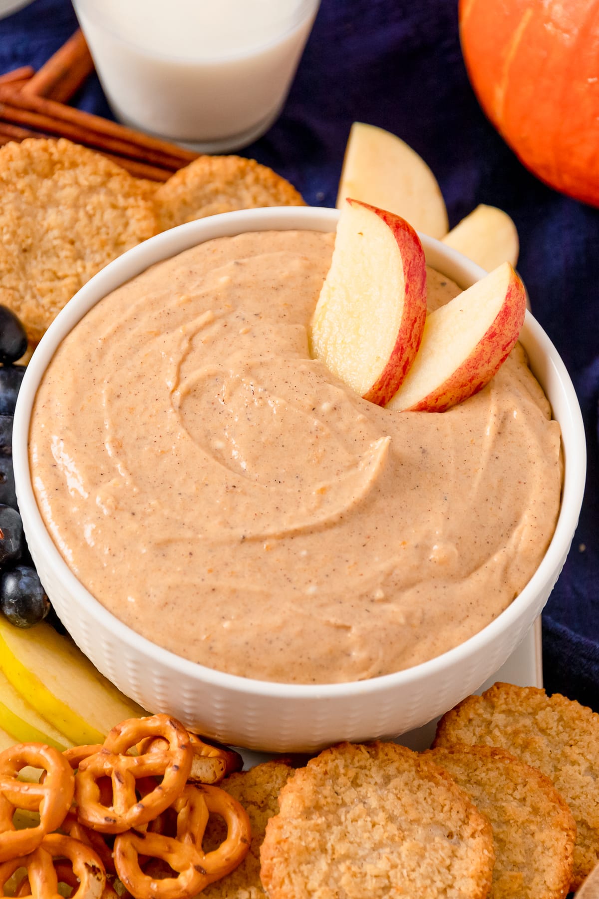 pumpkin dip with apple slices in a white serving dish