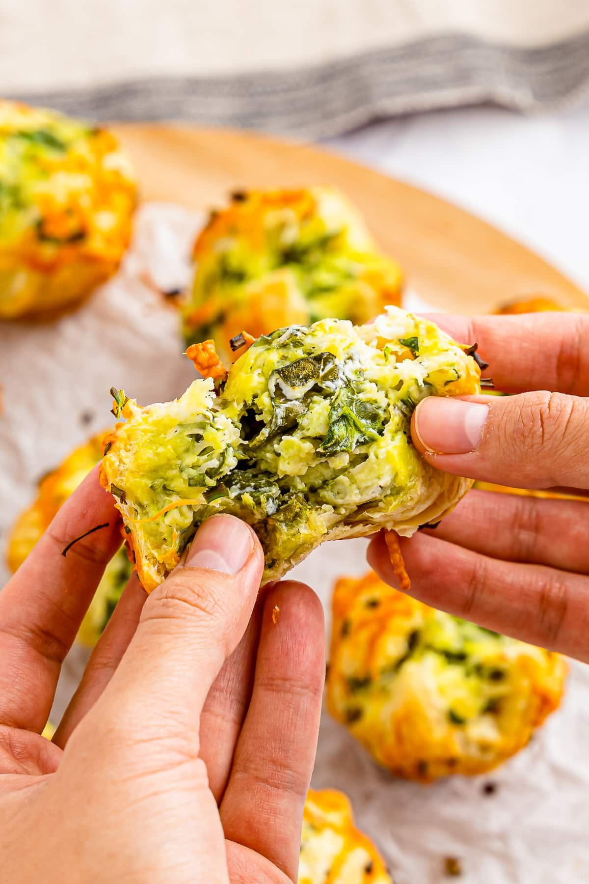 hands pulling apart a spinach puff to show the inside