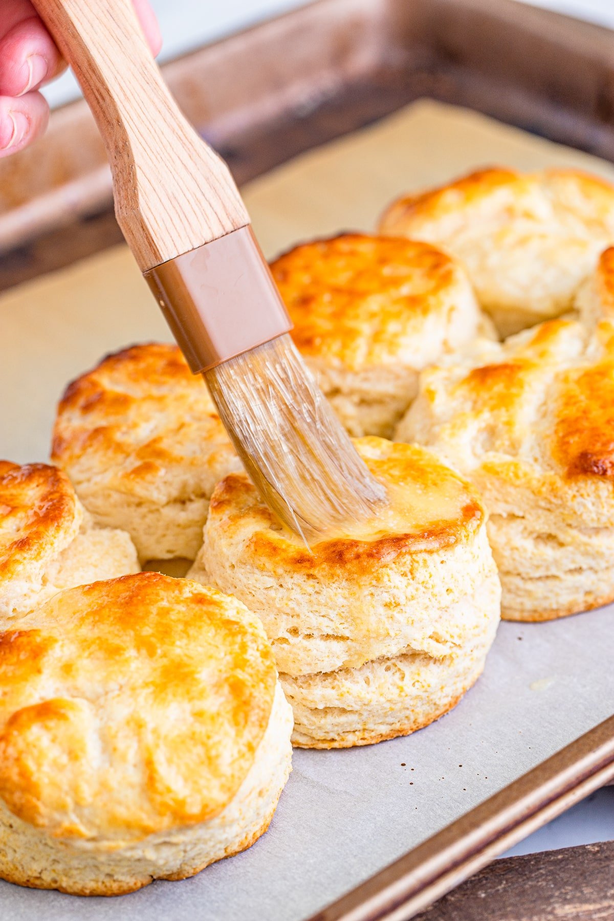 brushing butter on baked southern buttermilk biscuits