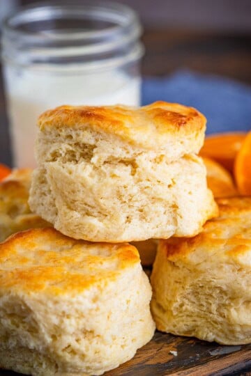 A stack of golden Southern buttermilk biscuits next to a jar of milk.