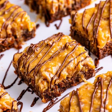 German chocolate brownies topped with coconut pecan frosting and chocolate drizzle cut into squares.