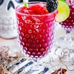 A deep red blackberry margarita in a hobnail goblet with a salt rim, lime wheel, and fresh blackberry garnish.
