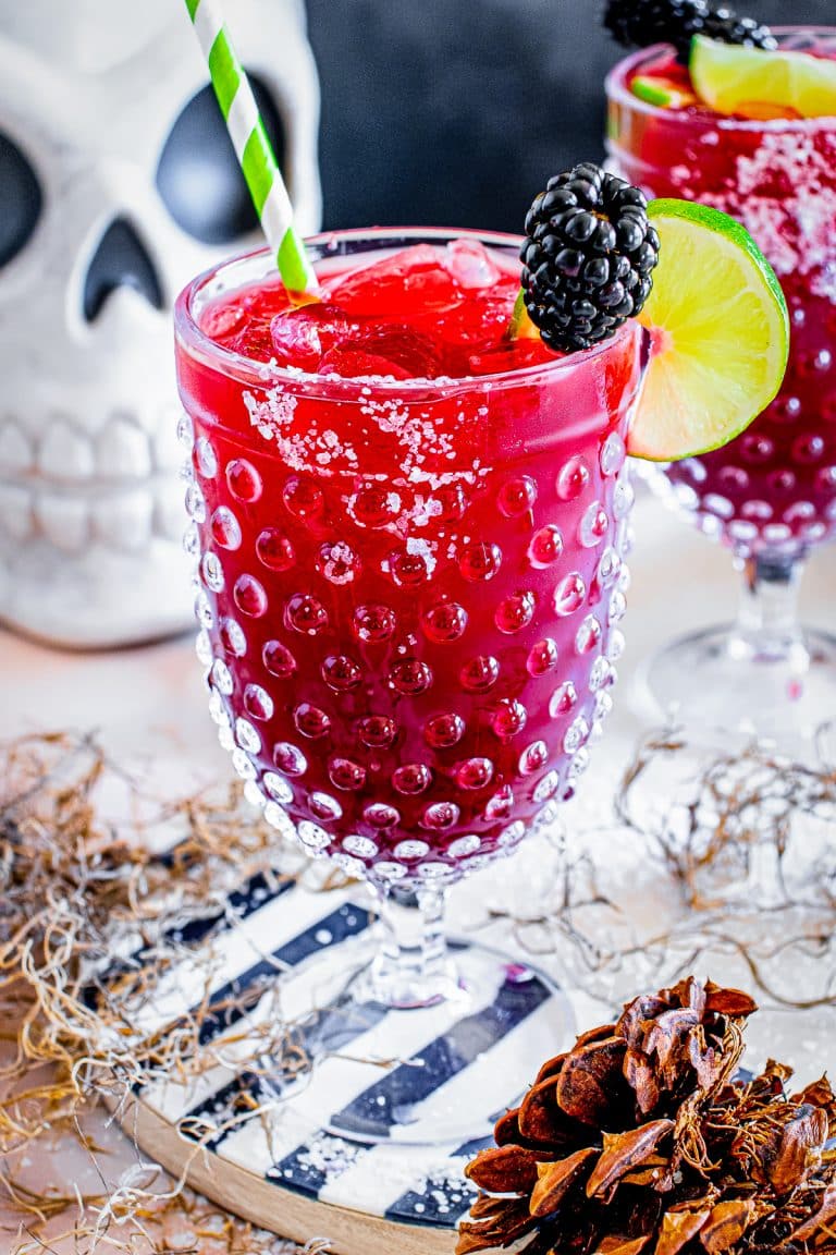 A deep red blackberry margarita in a hobnail goblet with a salt rim, lime wheel, and fresh blackberry garnish.