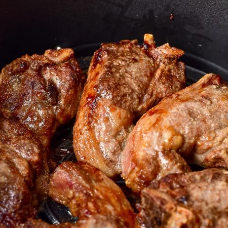 Juicy air fryer lamb chops plated with fresh herbs.